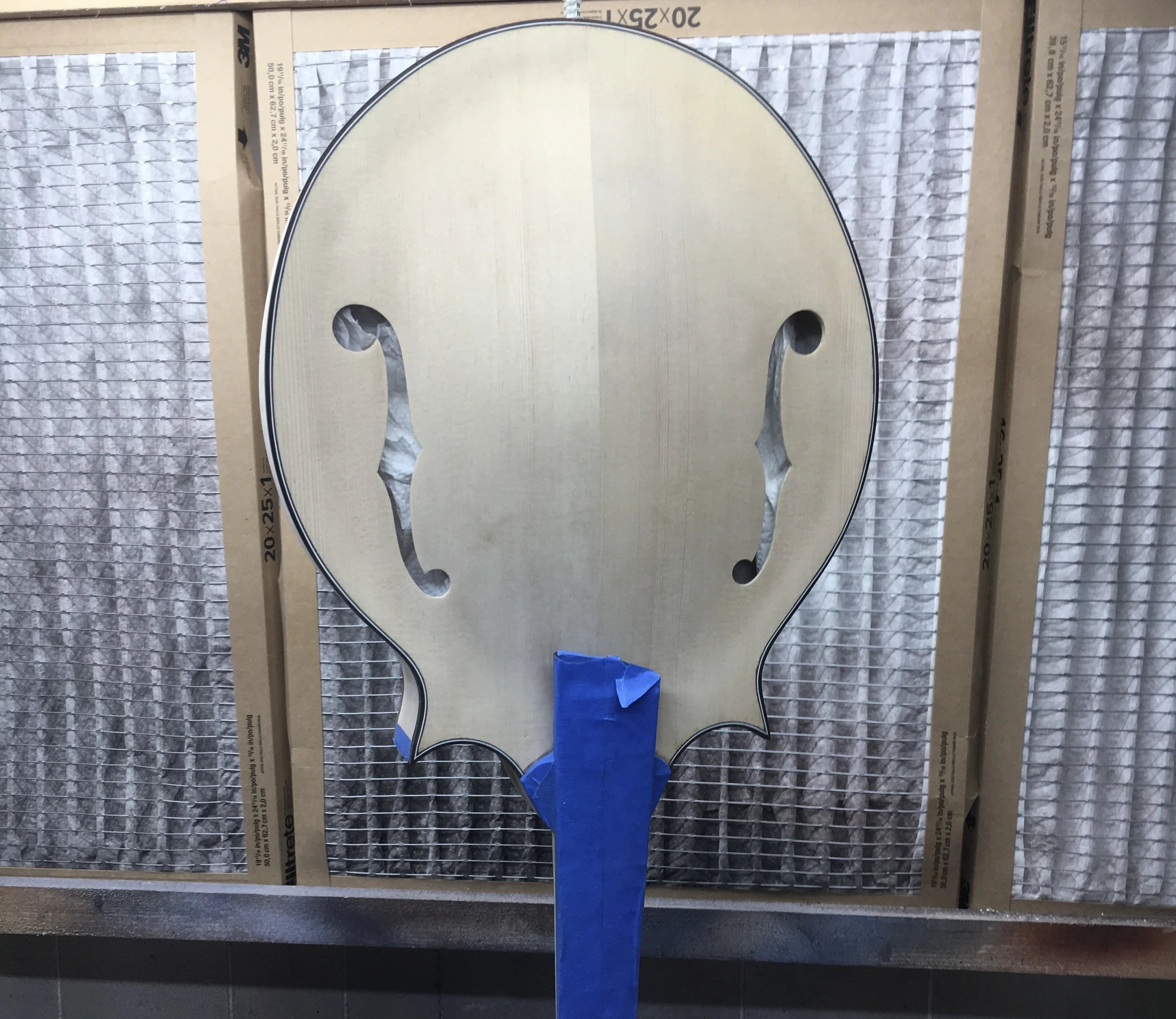 Mandolin body mounted on finishing stick in spray booth during finishing process
