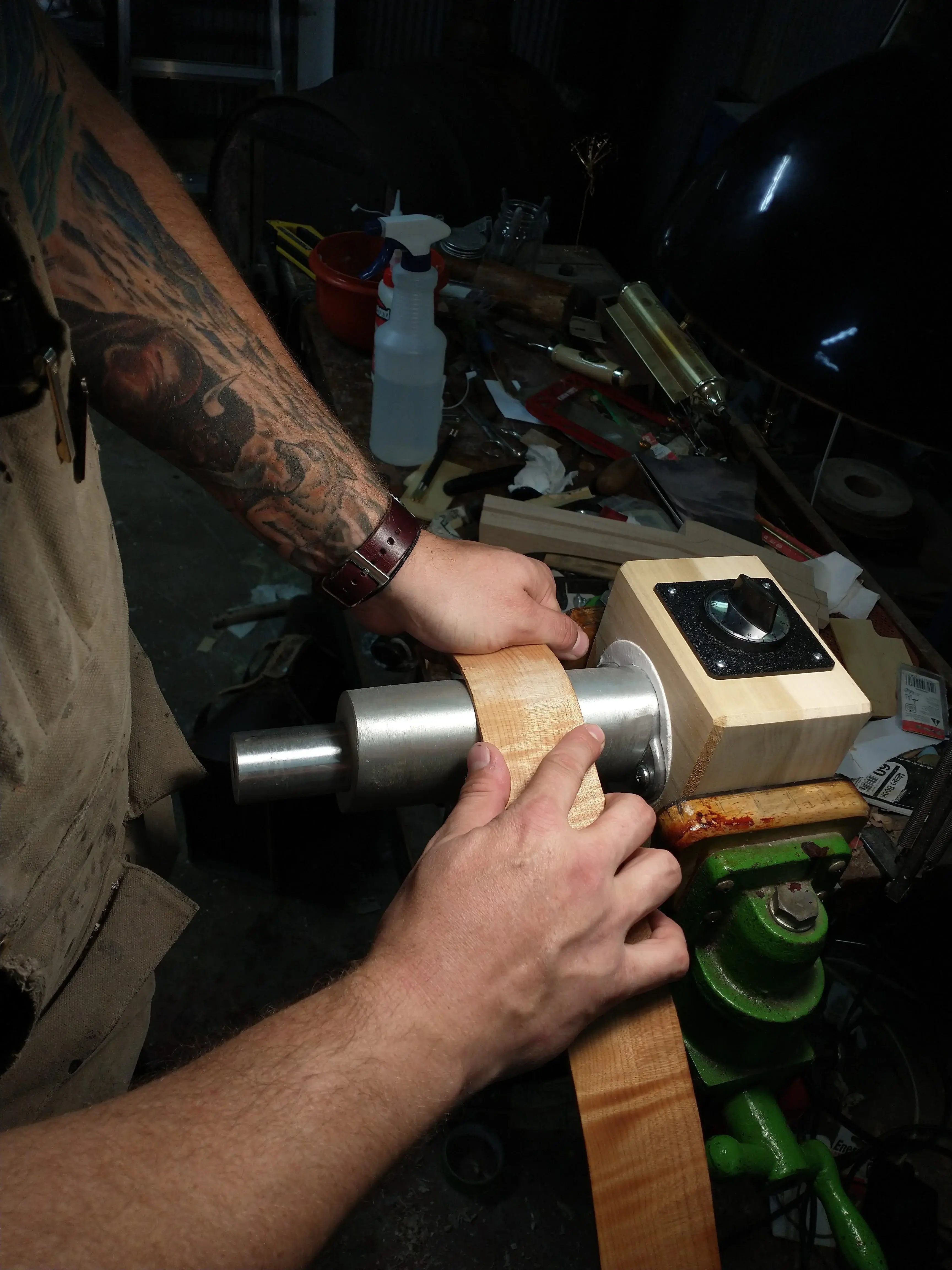 Hands guiding maple strip around heated bending form